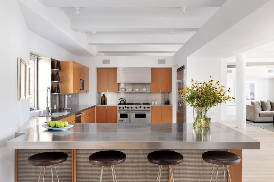 227 West 17th Street, Unit 7 Manhattan, NY 10011 - Photo 7 of 23 a kitchen with stainless steel appliances kitchen island granite countertop a table and chairs in it