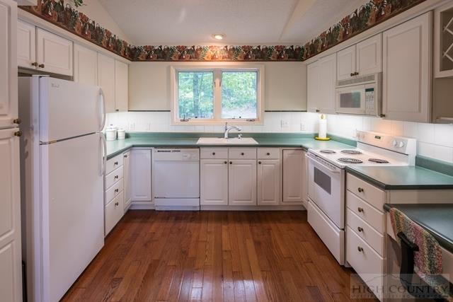 605 Pine Ridge Road Beech Mountain, NC 28604 - Photo 10 of 45 a kitchen with white cabinets white appliances and sink