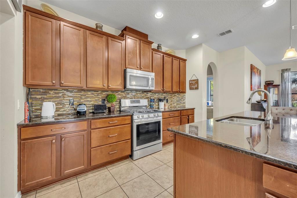 4277 Bugle Street Clermont, FL 34711 - Photo 15 of 35 a kitchen with stainless steel appliances granite countertop a refrigerator sink and cabinets