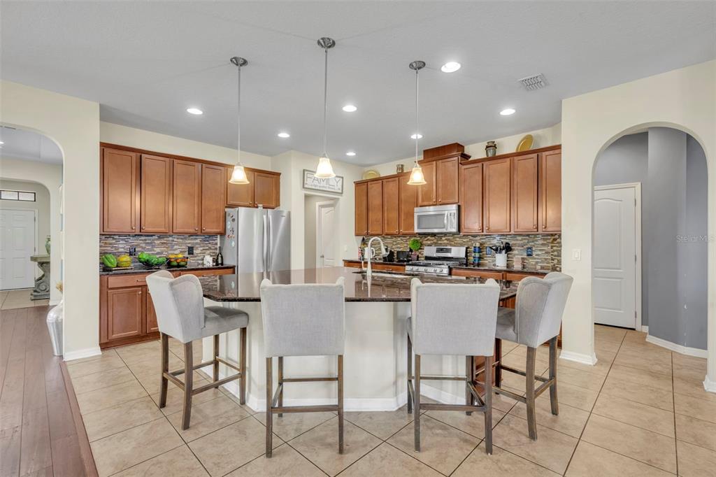 4277 Bugle Street Clermont, FL 34711 - Photo 9 of 35 a kitchen with stainless steel appliances kitchen island granite countertop a refrigerator and a dining table
