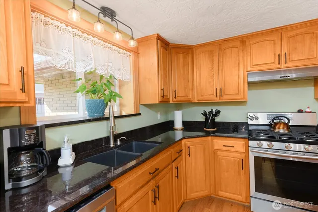 a kitchen with stainless steel appliances granite countertop a stove a sink and a microwave