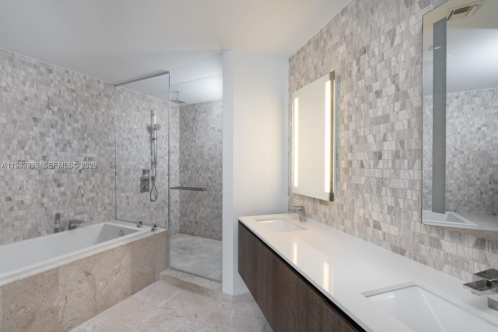 68 Southeast 6th Street, Unit 3402 Miami, FL 33131 - Photo 9 of 22 a bathroom with a granite countertop bathtub sink vanity and mirror