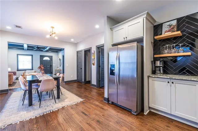 a dining room with stainless steel appliances granite countertop a refrigerator a sink a dining table and chairs with wooden floor