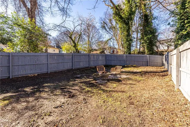 a view of a backyard with wooden fence and a large tree