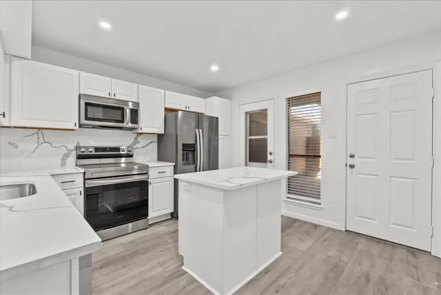 a kitchen with stainless steel appliances granite countertop a stove top oven a sink and a refrigerator