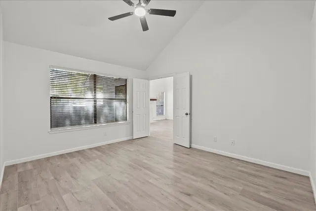 an empty room with wooden floor fan and windows