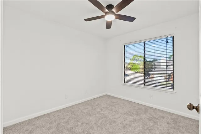 an empty room with a window and a ceiling fan
