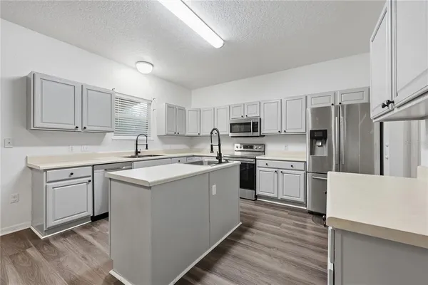 a kitchen with refrigerator a sink and white cabinets
