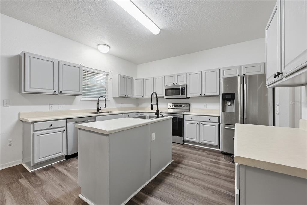 1348 Southwest 245th Way Newberry, FL 32669 - Photo 12 of 38 a kitchen with refrigerator a sink and white cabinets