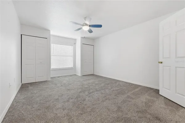 an empty room with closet and windows