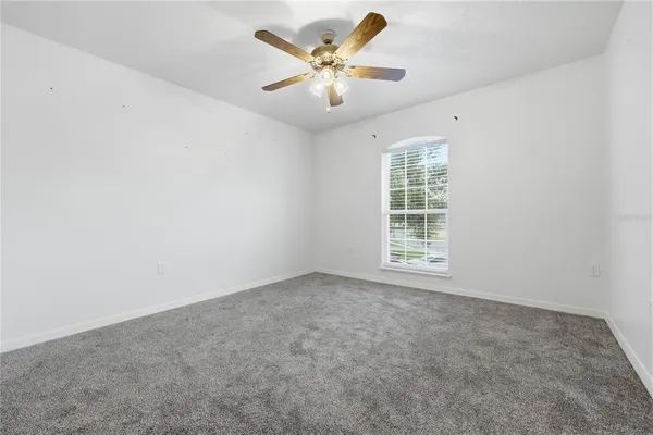 an empty room with windows and ceiling fan