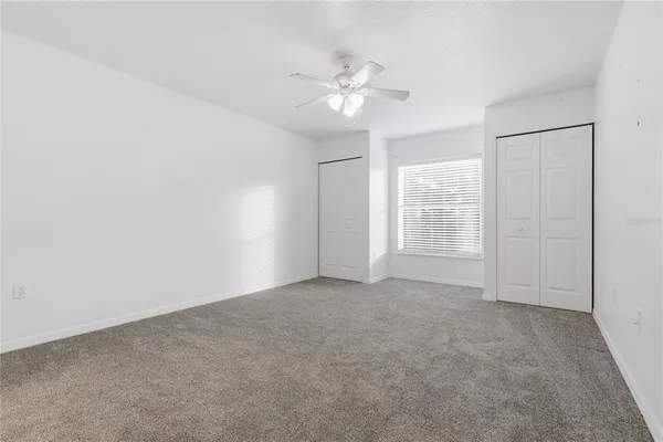 an empty room with windows and fan