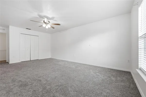 an empty room with a window and a ceiling fan