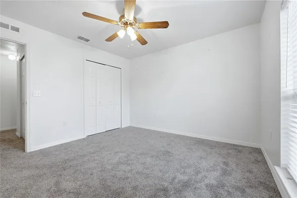 an empty room with a chandelier fan and windows