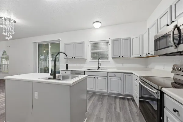 a kitchen with stainless steel appliances granite countertop a sink dishwasher a stove and white cabinets with wooden floor