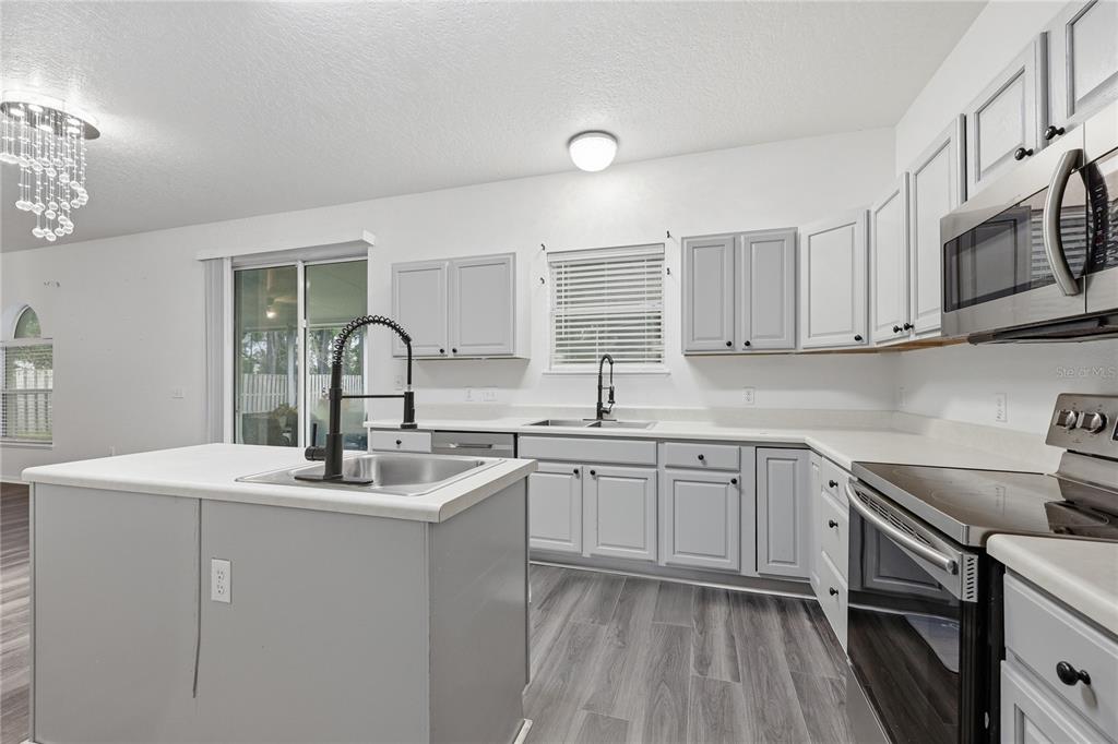 1348 Southwest 245th Way Newberry, FL 32669 - Photo 10 of 38 a kitchen with stainless steel appliances granite countertop a sink dishwasher a stove and white cabinets with wooden floor
