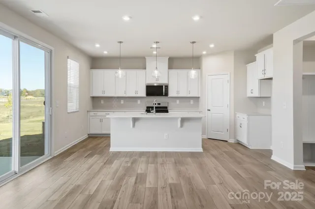 a large kitchen with kitchen island white cabinets and stainless steel appliances