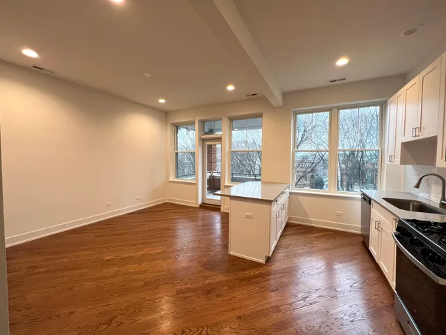 a large kitchen with wooden floor and stainless steel appliances