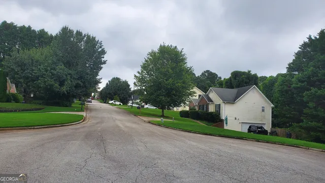 a view of a house with a yard and large trees