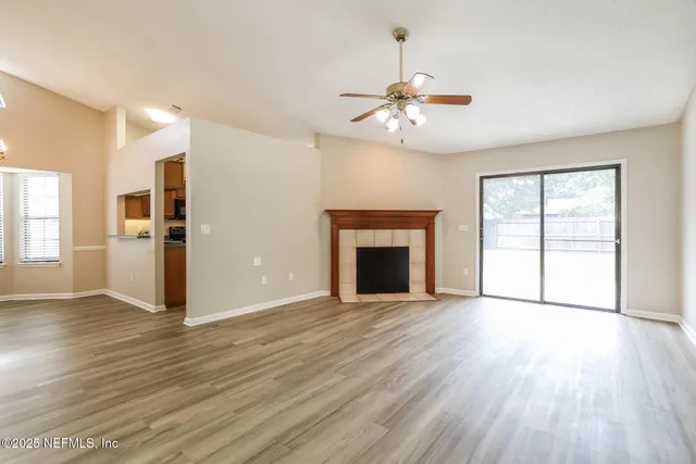 an empty room with wooden floor fireplace and windows