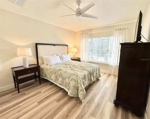 a bedroom with a bed flat screen tv and a large window