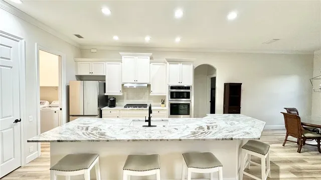 a kitchen with stainless steel appliances kitchen island granite countertop a kitchen island and chairs in it