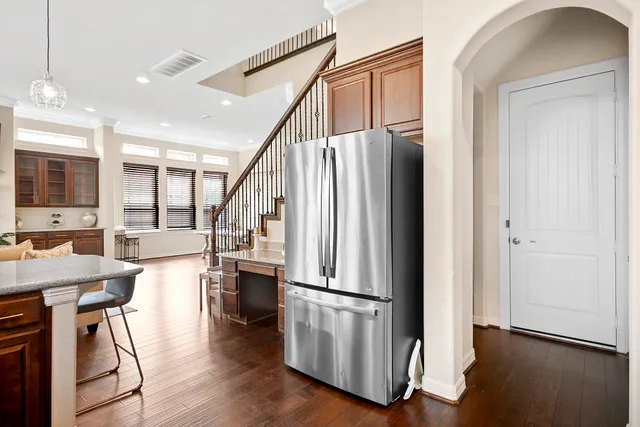 a kitchen with stainless steel appliances granite countertop a refrigerator a stove a sink and a dining table with wooden floor