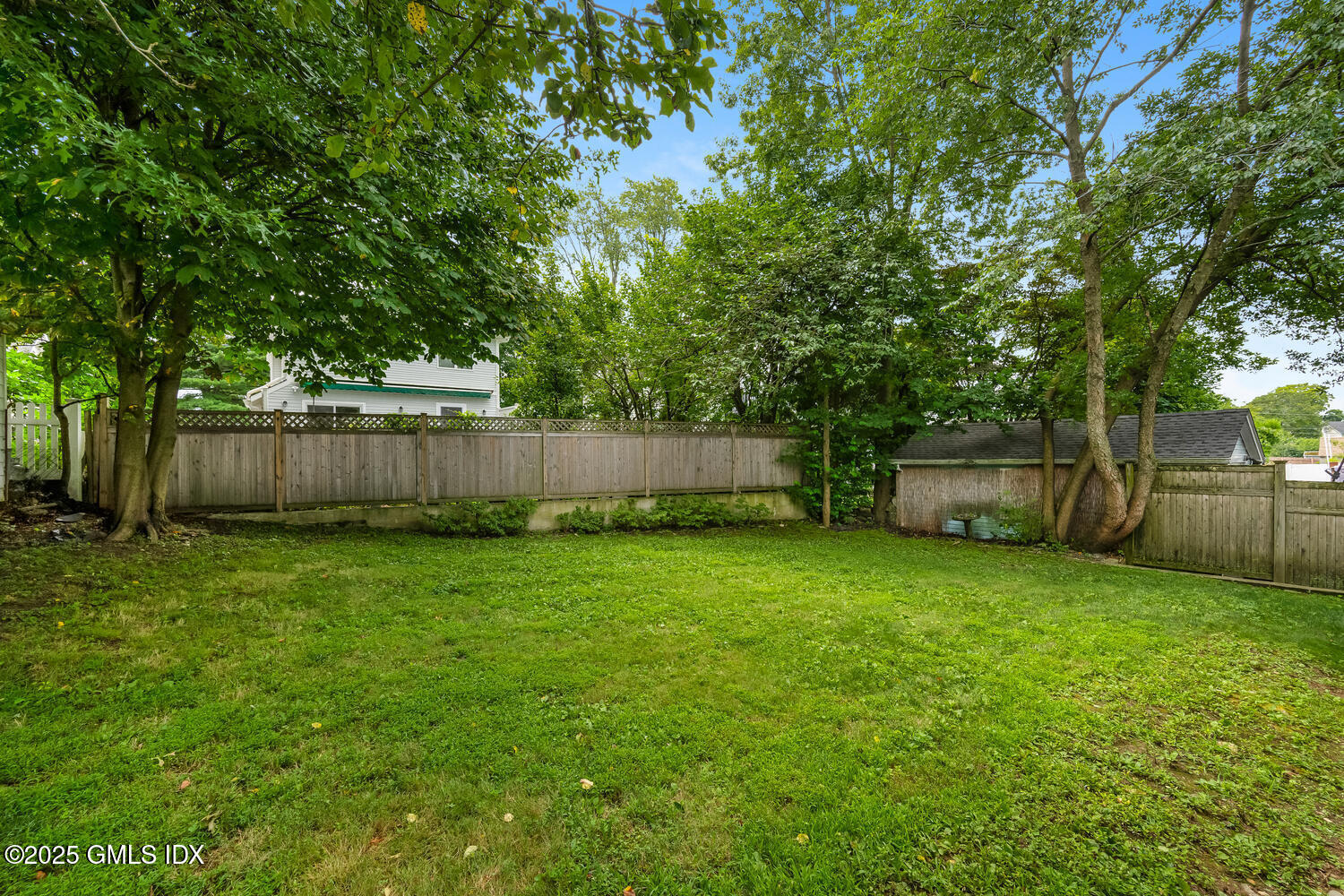 19 High Street Greenwich, CT 06830 - Photo 20 of 25 a view of a backyard with large trees and wooden fence