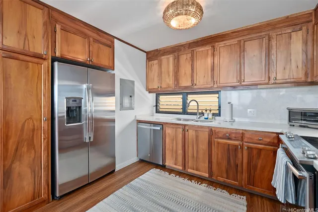 a kitchen with stainless steel appliances granite countertop a refrigerator a sink dishwasher and wooden cabinets with wooden floor