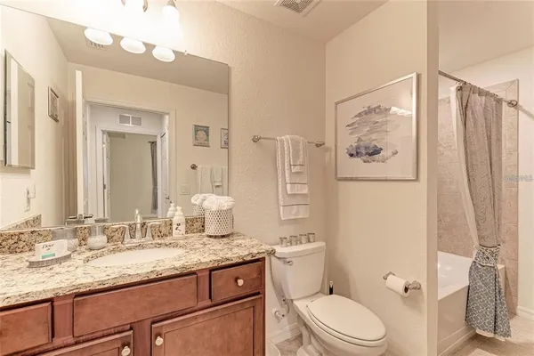 a bathroom with a granite countertop sink mirror vanity and toilet