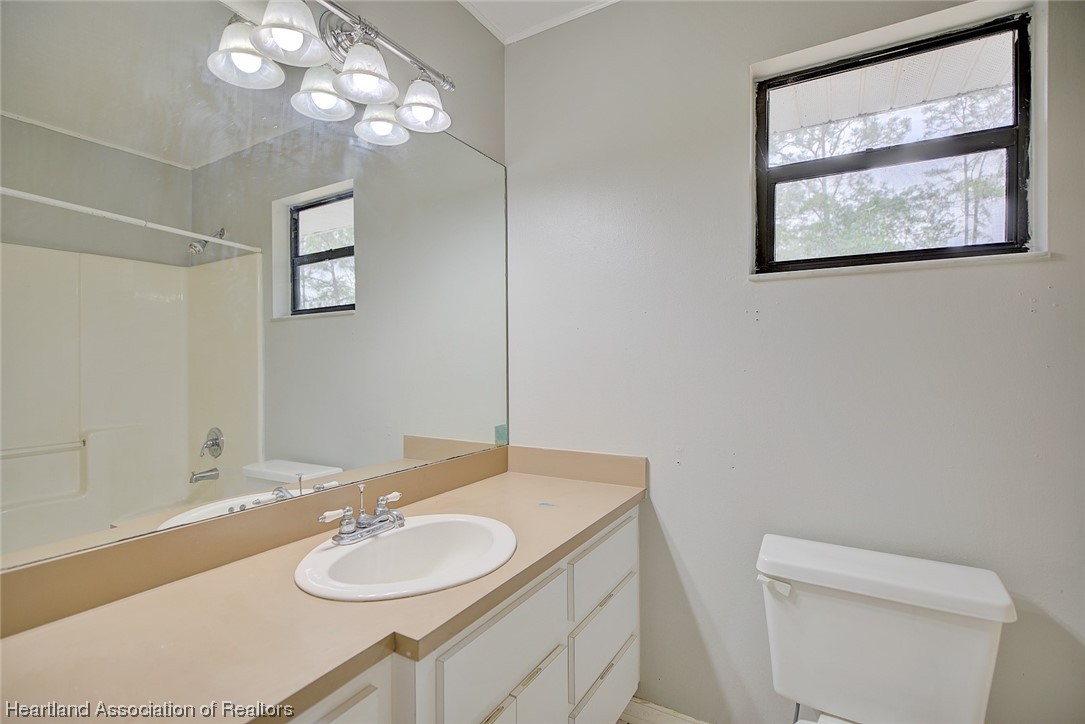 6304 Gunner Terrace Sebring, FL 33875 - Photo 9 of 41 a bathroom with a granite countertop sink a mirror and a toilet