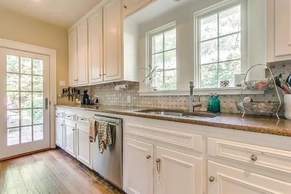 a kitchen with granite countertop white cabinets and a window