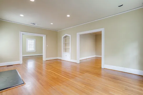 a view of an empty room with wooden floor and windows