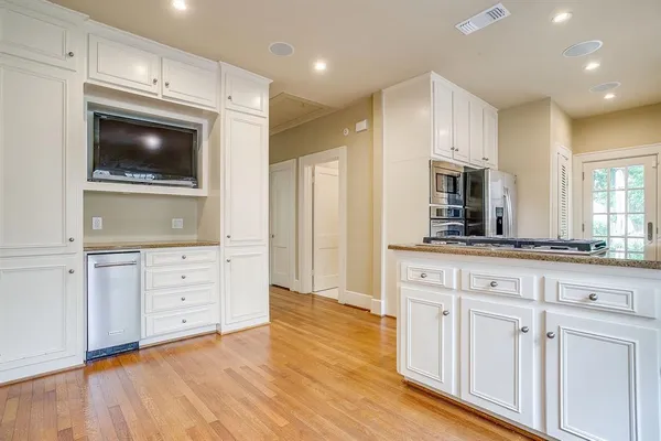 a living room with stainless steel appliances kitchen island granite countertop a stove a sink and a white cabinets