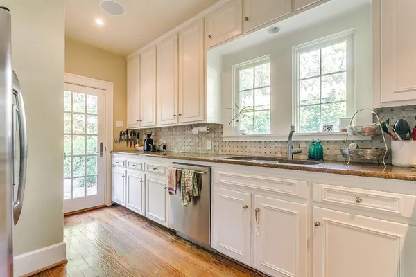 a kitchen with granite countertop white cabinets and a window