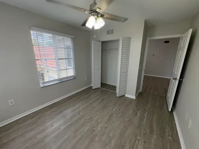a view of empty room with wooden floor and fan
