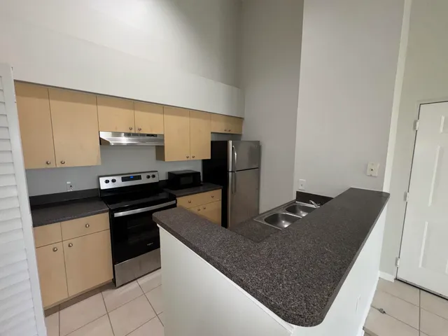 a kitchen with granite countertop a refrigerator a stove and white cabinets