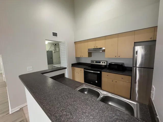 a kitchen with granite countertop a refrigerator and a stove top oven