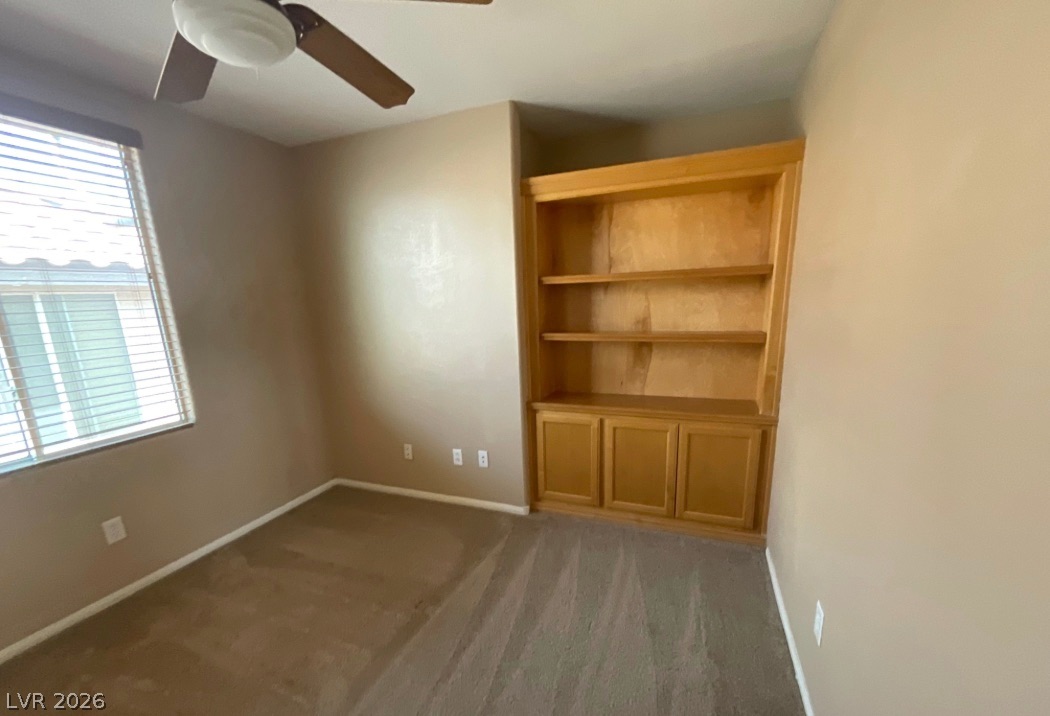 10841 Paradise Road Henderson, NV 89052 - Photo 24 of 35 Well-lit room featuring soft carpeting and a spacious built-in bookcase with lower cabinetry.