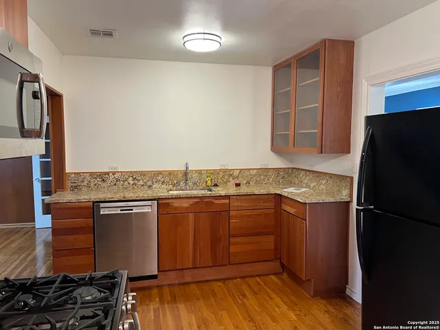 a kitchen with stainless steel appliances granite countertop a refrigerator and a stove top oven