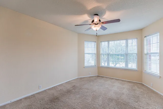 an empty room with windows and fan