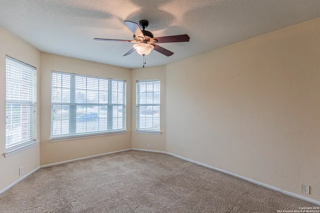 an empty room with windows and fan