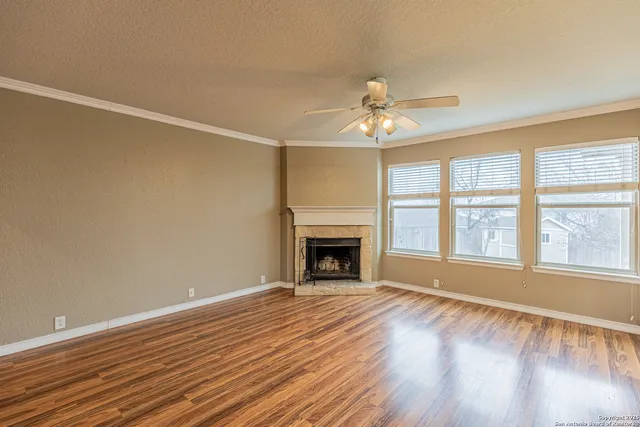 a view of an empty room with a window and wooden floor