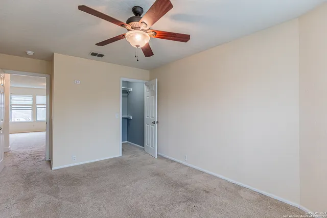 an empty room with closet and a ceiling fan