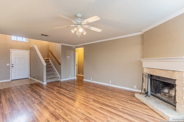 an empty room with wooden floor staircase and a kitchen