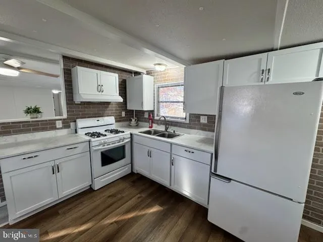 a white kitchen with sink stove and refrigerator