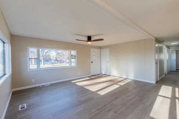 a view of an empty room with wooden floor and a window