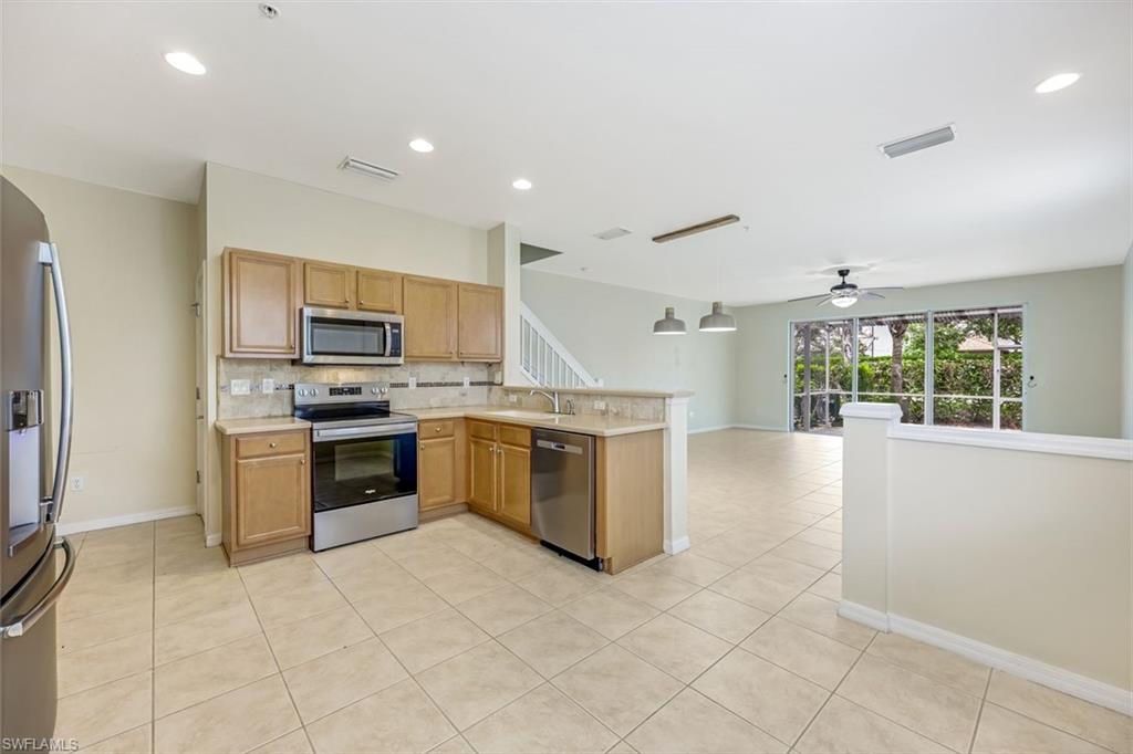 16162 Ravina Way, Unit 65 Naples, FL 34110 - Photo 6 of 22 a large kitchen with stainless steel appliances granite countertop a stove a sink dishwasher a refrigerator and a microwave oven with large cabinets