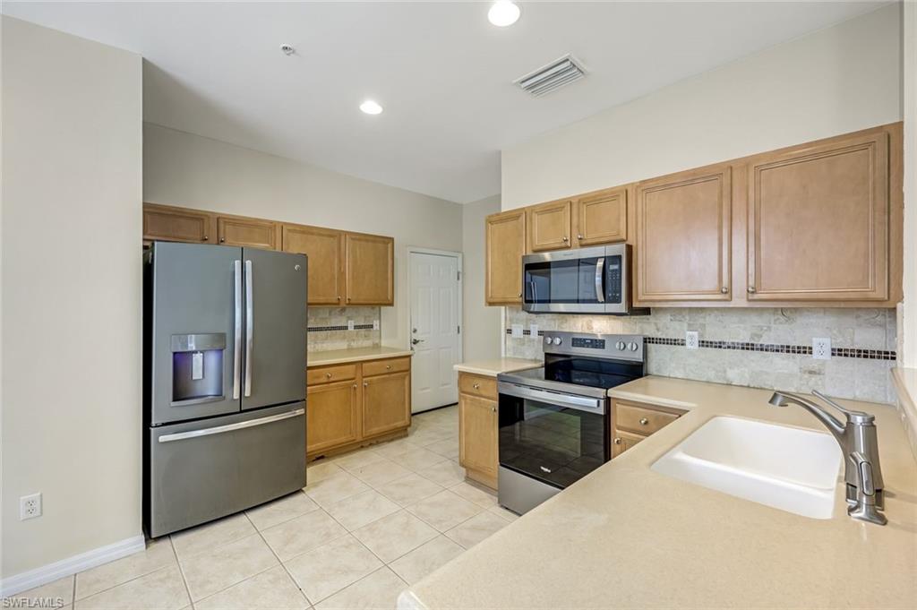 16162 Ravina Way, Unit 65 Naples, FL 34110 - Photo 8 of 22 a kitchen with granite countertop a refrigerator and microwave