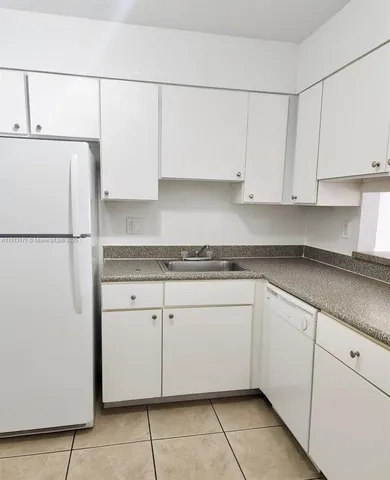 a kitchen with granite countertop cabinets and refrigerator